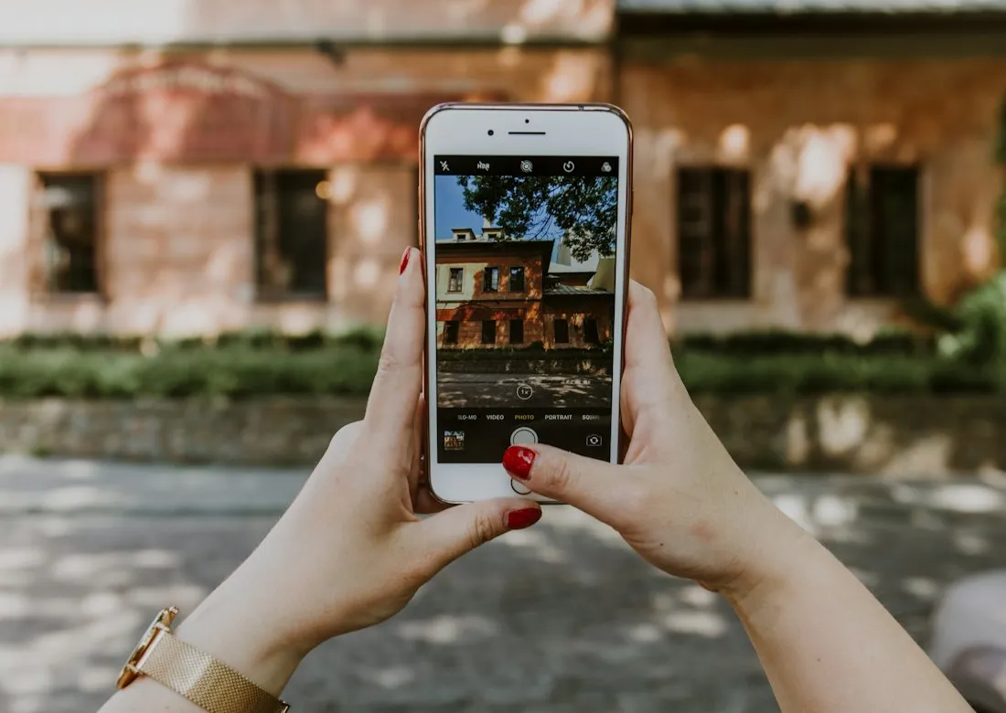 Deux mains photographient la façade d'une maison avec un téléphone