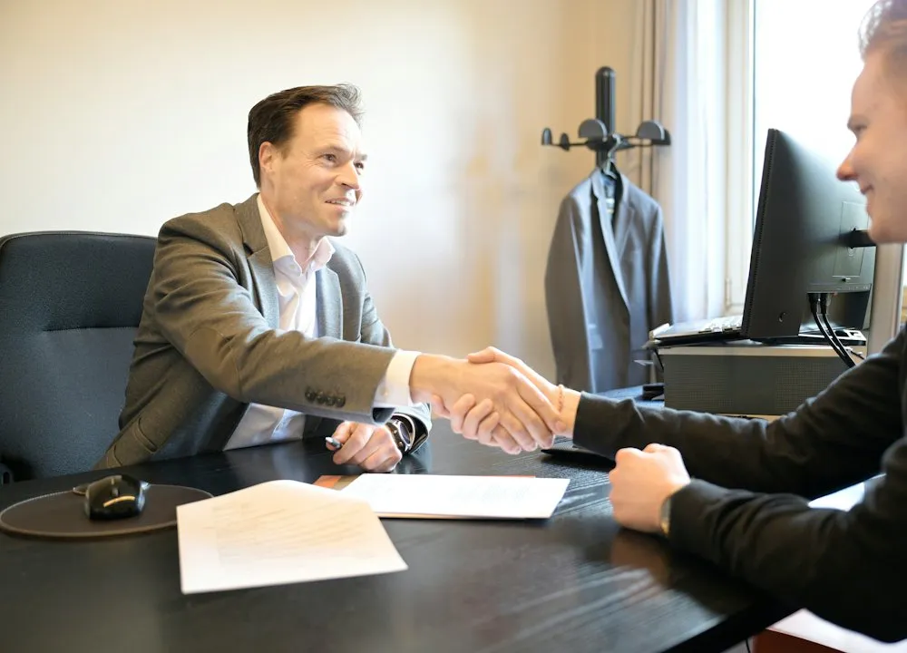 Deux hommes se serrent la main au-dessus d'un bureau