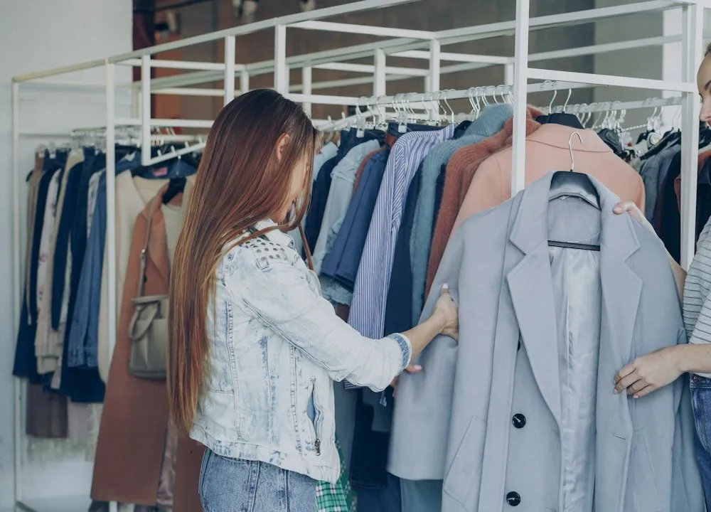 Une vendeuse présente un manteau à une cliente dans une boutique